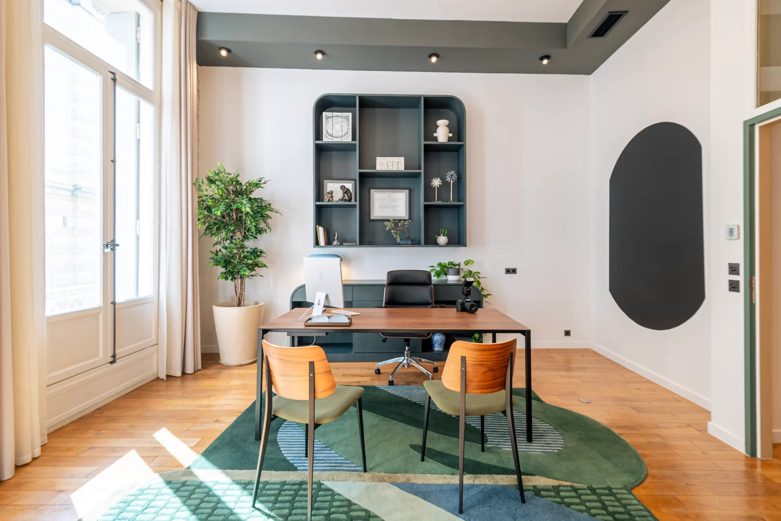 Le bureau de consultation, avec deux fauteuils face au bureau en bois et une bibliothèque murale.